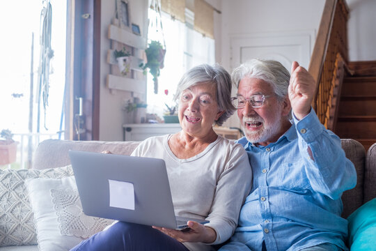 Overjoyed Middle Aged Mature Family Couple Looking At Laptop Screen, Celebrating Online Lottery Win Or Auction Bid, Excited Of Reading Email With Great News, Feeling Happiness Together At Home..