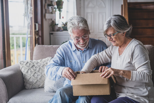Happy mature aged older family couple unpacking carton box, satisfied with internet store purchase or unexpected gift, feeling excited of fast delivery shipping service, positive shopping experience..