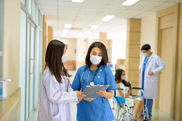 Obraz premium Two doctors were discussing work, wearing white masks. In the corridor of the hospital clinic.