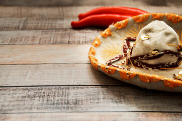 Festive Mexican headdress - sombrero on wooden boards and red pepper. Symbols of Mexico, background for the holiday Cinco de mayo. Space for text on the left.