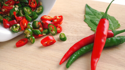 Chili red and green sliced in white ceramic bowl on wooden cutting board, Red hot chili peppers is an herb with medicinal properties, Spicy seasoning ingredients (Macro shot).