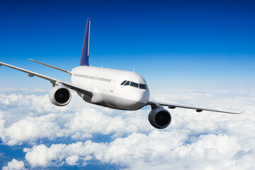 Naklejka na ściany i meble Passenger jetplane flying above clouds