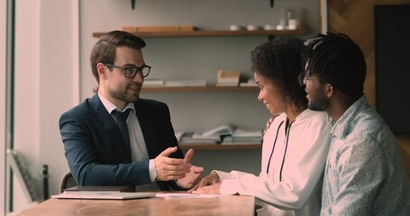 Smiling pleasant trusted young professional realtor or financial advisor in formal wear explaining offer issues to happy african american couple clients at meeting in office, shaking hands making deal - Powered by Adobe