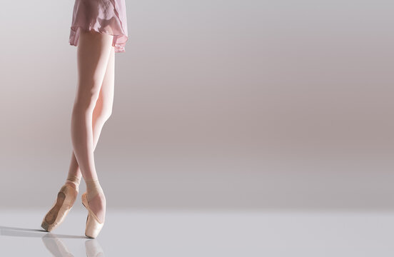 Ballerina's feet in pointe shoes standing isolated on white background