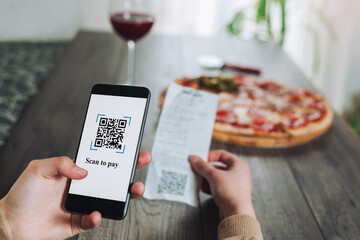 Women's hands using the phone to scan the qr code to pay pizza. Scan to get discounts or pay for...