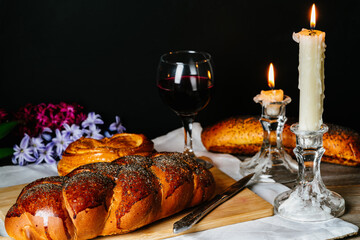 Shabbat Shalom. Challah bread, shabbat wine and candles on wooden table.