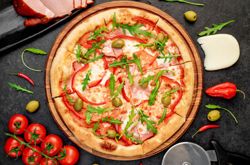 pizza with ham, tomatoes, cheese on a stone background