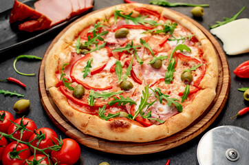 pizza with ham, tomatoes, cheese on a stone background