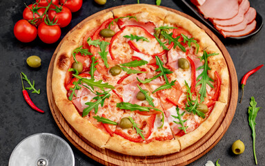 pizza with ham, tomatoes, cheese on a stone background