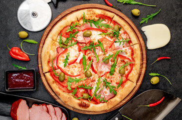 pizza with ham, tomatoes, cheese on a stone background