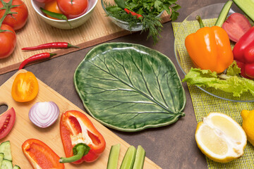 Different vegetables for cooking and empty plate in the form of green leaf. Diet, fasting, vegan, vegetarian, healthy raw food concept