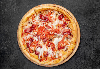 pizza with sausages, mushrooms, tomatoes and cheese on a stone background