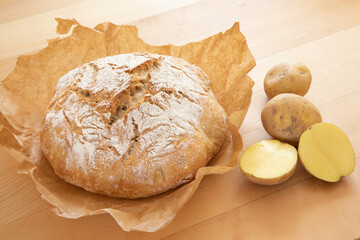 Frisch gebackenes Kartoffelbrot mit Kartoffeln auf Ahorntisch