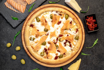 pizza with salmon, cheese and olives on a stone background
