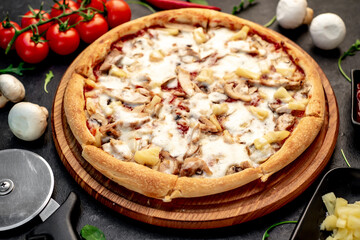 pizza with chicken, mushrooms and pineapple on a stone background