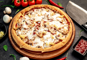 pizza with chicken, mushrooms and pineapple on a stone background