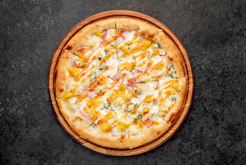 delicious pizza with ham, cheese, pineapple, mango on a stone background