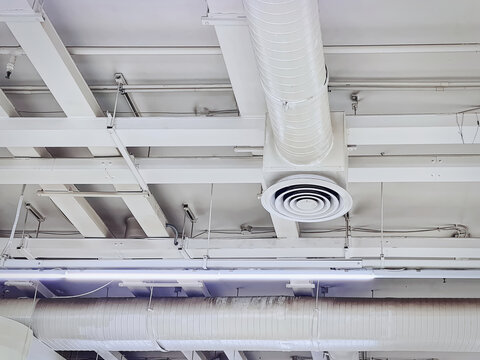 Low Angle View of White Insulated Air Conditioning Duct with Round Grille Diffuser