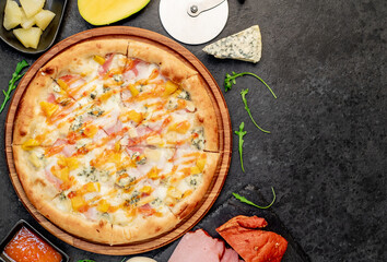delicious pizza with ham, cheese, pineapple, mango on a stone background  with copy space for your text