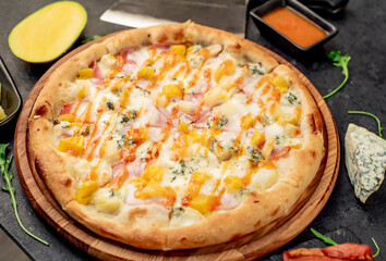 delicious pizza with ham, cheese, pineapple, mango on a stone background