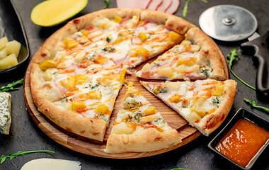 delicious pizza with ham, cheese, pineapple, mango on a stone background