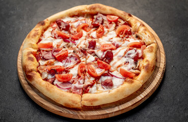 pizza with sausages, mushrooms, tomatoes and cheese on a stone background