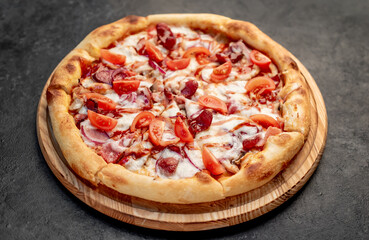 pizza with sausages, mushrooms, tomatoes and cheese on a stone background