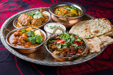 Traditional Indian curry dishes served with rice and pita bread as close-up on a traditional thali