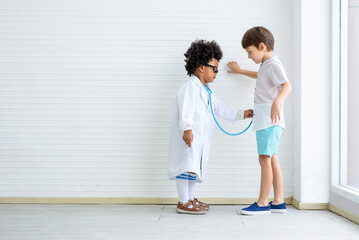 Fototapeta premium The child wears a doctor's suit and uses a stethoscope to examine the prostate gland..