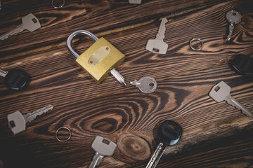 Studio photo of a lock with a broken key in it on a wooden background. Lots of other new keys...