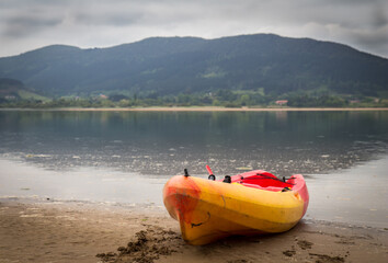 kayak on the shore of a quiet lake ready to use