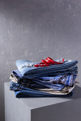 Denim jeans and belt at old grey cube near grey wall background texture.  Stack classic jeans