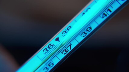 Close-up frame of a medical thermometer. Measurement of readings of the patient's body temperature. Good color 4k. Search for the desired position of the mercury thermometer. Changing the angle