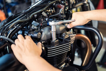 Mechanic using a wrench and socket on cylinder head of a motorcycle .maintenance,repair motorcycle concept in garage .selective focus