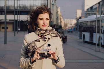 A young woman taking a photo with a retro film camera and smiles