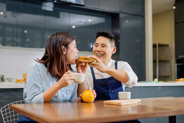 A couple with a breakfast sandwich Inside the kitchen background.