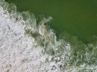 Aerial drone image of foamy waves washing up on the beautiful sandy beach of Island Beach State Park in New Jersey creating colorful abstract images