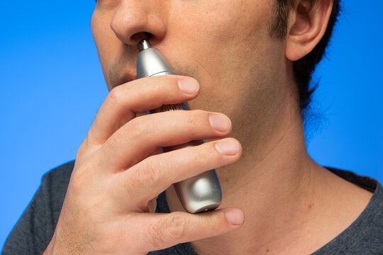 Caucasian male using nose hair trimmer unrecognizable face crop close up studio shot