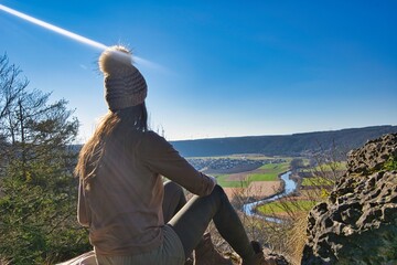 Junge Frau geniest die Aussicht auf Kipfenberg im Altmühltal, Bayern, Deutschland bei einem klaren, blauen Himmel.