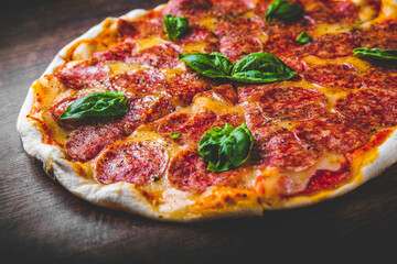 Pepperoni Pizza with Mozzarella cheese, salami, Tomato sauce, pepper, Spices and Fresh basil. Italian pizza on wooden table background