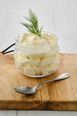 Closeup view of fat sour cream in a glass pot.