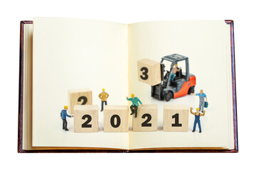 miniature worker with aged book isolated on white background.