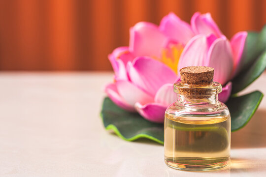 bottle of aroma essential oil with candle and pink lotus on stone table, spa concept.