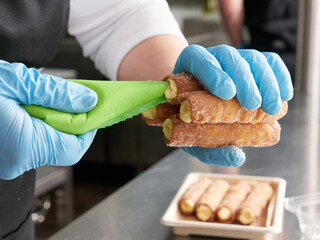 chef preparing cream-filled cannoli, no faces shown
