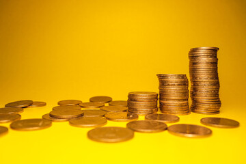 Stack of golden coins on yellow background with earning profit concept. Gold coins or currency of business. Coin purse banknotes.
