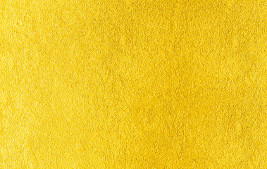 Gold wall texture background. Yellow shiny gold foil paint on wall surface with light reflection,...