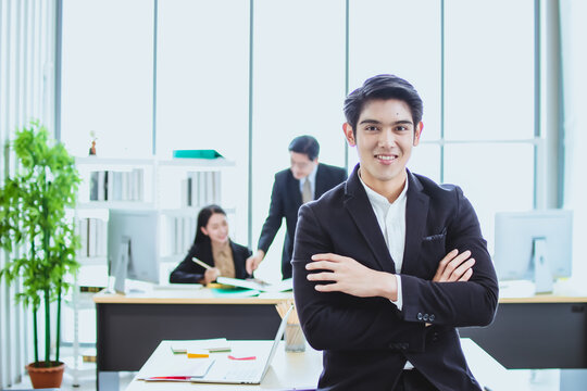 young asian business man. smile face. sitting and standing in office. talk business. phone call with official working background. looking camera cross arm copy space