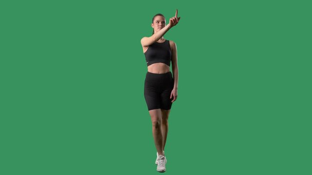 Young fitness woman using various interactive touch screen gestures. Full body on green screen chroma key background. 