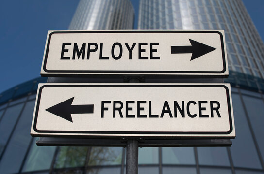 Employee versus freelancer road sign with two arrows on business skyscraper background. White two street sign with arrows on metal pole. Two way road sign with text.