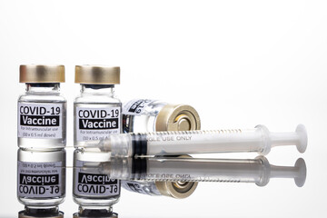 Covid-19 vaccine vial with syringe concept on reflective surface